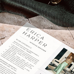 May include: A resume for Erica Harper, an interior designer, is displayed on a light-colored stone surface. The document lists work experience, including roles at Design Studio X and Design Firm Y, with details on project management and design achievements.