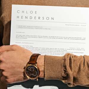 Könnte beinhalten: Ein Lebenslauf mit dem Namen Chloe Henderson oben. Der Lebenslauf enthält Abschnitte für Zusammenfassung, Berufserfahrung und Ausbildung. Der Lebenslauf wird von einer Person gehalten, die einen braunen Pullover und eine goldene Uhr trägt.