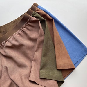 May include: Four pairs of underwear in different colors: light brown, dark brown, olive green, and light blue. The underwear is made of a soft, comfortable fabric and has a wide elastic waistband.