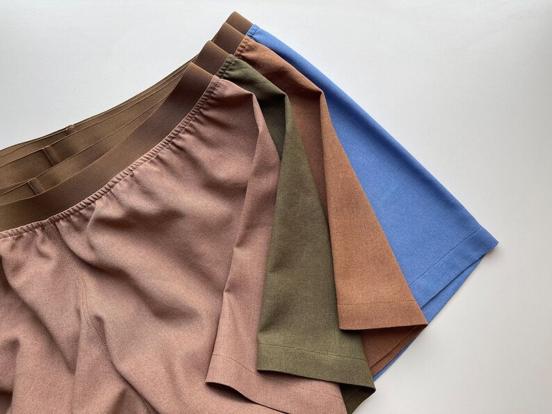 May include: Four pairs of underwear in different colors: light brown, dark brown, olive green, and light blue. The underwear is made of a soft, comfortable fabric and has a wide elastic waistband.