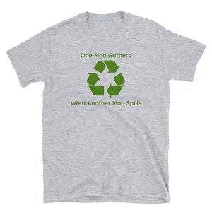 May include: A light grey t-shirt featuring the text "One Man Gathers What Another Man Spills" in green, and a green recycling symbol. The shirt is made of a soft material and has short sleeves.