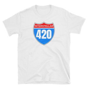 May include: White t-shirt featuring a shield design with the word "INTERSTELLAR" in red above the number "420" in white on a blue background. The design is outlined in black.