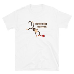 May include: White t-shirt featuring a cartoon monkey holding a red wrench. The text "The One Thing We Need Is" is printed above the monkey. The shirt is made of a soft, comfortable material.