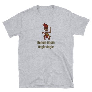 Può includere: T-shirt grigio chiaro con un disegno di un personaggio tiki dei cartoni animati che tiene in mano una mazza di legno. Il tiki è marrone, rosso e giallo. Sotto il tiki c'è la scritta "Boogie Oogie Oogie Oogie" in marrone. La maglietta è in materiale morbido.
