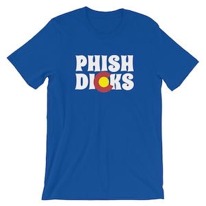 Puede incluir: Camiseta azul real con la inscripción blanca "PHISH DICKS" en forma de arco. La bandera del estado de Colorado está centrada debajo. La camiseta está hecha de un material suave.