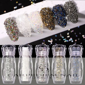 May include: Six small bottles of nail glitter in various colors, including clear, white, iridescent, gold, blue, and black. The bottles are clear glass with a diamond-shaped top and a label that reads "CARPELDIEMNAIL COLOR YOUR LIFE".