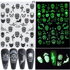May include: A sheet of glow-in-the-dark nail stickers with a variety of designs, including skulls, cats, snakes, and stars. The stickers are on a white background and are ready to be applied to nails. #5+