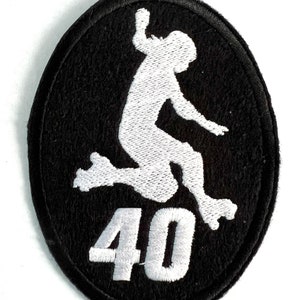May include: Black oval patch with a white embroidered silhouette of a person roller skating and jumping. The number "40" is embroidered in white below the skater. The patch has a black border.