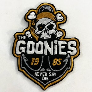 May include: A black and gold embroidered patch with a skull and crossbones, an anchor, and the text "The Goonies 79 85 Never Say Die".