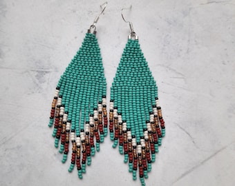 May include: Teal, brown, white and black beaded earrings with a fringe design.