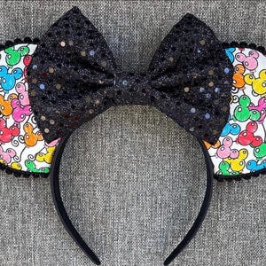 Puede incluir: Diadema de orejas de Mickey Mouse en blanco y negro con un lazo negro de lentejuelas. Las orejas están cubiertas de una tela blanca con globos de Mickey Mouse de colores impresos.