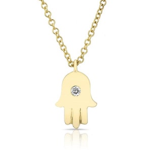 May include: A gold chain necklace with a hamsa hand pendant featuring a single diamond in the center.