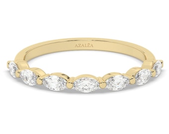 May include: A gold band ring with a row of marquise-shaped diamonds. The ring is engraved with the word "AZALEA".