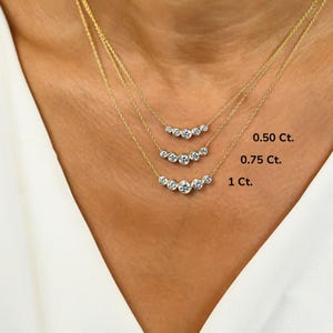 May include: Three gold necklaces with graduated sizes of round diamonds. The necklaces are layered on a model's neck. The diamonds are labeled 0.50 Ct., 0.75 Ct., and 1 Ct.