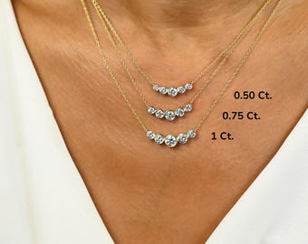 Può includere: Tre collane d'oro con diamanti rotondi di dimensioni graduate. Le collane sono sovrapposte sul collo di una modella. I diamanti sono etichettati 0,50 Ct, 0,75 Ct e 1 Ct.