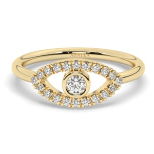 May include: A gold ring with a diamond-encrusted eye design. The ring is set with a single round diamond in the center of the eye. The ring is inscribed with the word "AZALEA".