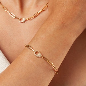 May include: A gold chain bracelet with a pave diamond clasp. The bracelet is made of linked, rectangular shapes.
