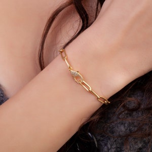 May include: A gold chain bracelet with a small, pave-set clasp. The bracelet is made of a thick, linked chain.