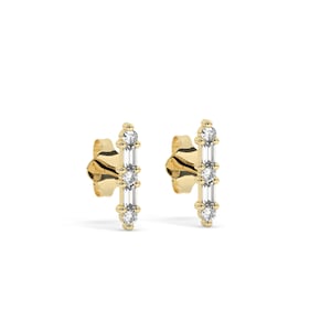 May include: A pair of gold earrings with a vertical line of four small diamonds. The diamonds are set in a prong setting and are all the same size. The earrings are a simple and elegant design.