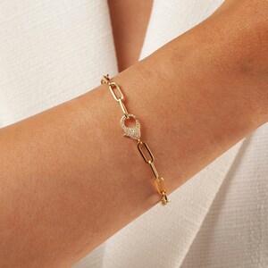 May include: A gold chain bracelet with a pave diamond clasp. The bracelet is made of linked oval shapes.