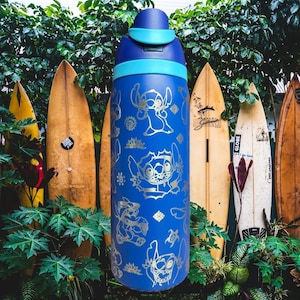 May include: A blue water bottle with a silver Stitch character design. The bottle has a light blue lid and accents. The background features surfboards and green foliage, evoking a tropical atmosphere.