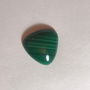 May include: A green malachite cabochon with a triangular shape and a striated pattern.