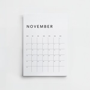 Gedruckte Seite des minimalistischen deutschen Kalenders 2026, ein Monat im Hochformat, schwarze Linien, moderne Schrift, weißes A4-Papier auf hellem Holzuntergrund fotografiert.