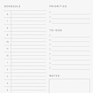 Close-up of a minimalist daily planner PDF printed on A4 paper with half-hourly schedule and to-do list columns, photographed flat on a light wooden surface with a pencil and paper clips in view.