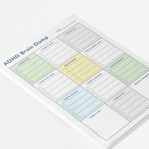 Close-up of compact ADHD planner pad placed on a clean desk, showing boxes for calls, research, appointments, and tasks — printed in soft pastel tones.