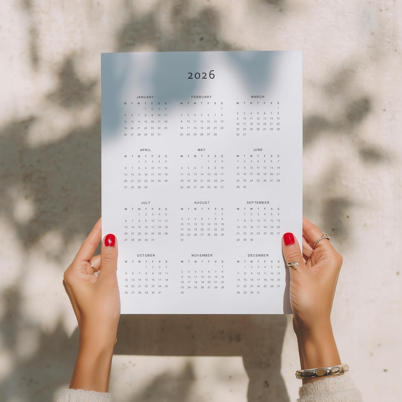 Printable yearly calendar 2026 PDF shown on US Letter paper with portrait layout, featuring complete year grid, clean lines and grey typography, styled on a minimal desk flat lay background