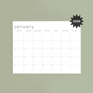 Printed January 2026 monthly planner page on white paper, lying flat on a light wooden table. Landscape layout shows a clean grid with fine gray lines, black dates, and slim modern font, Monday start format.