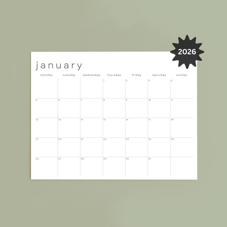 Printed January 2026 monthly planner page on white paper, lying flat on a light wooden table. Landscape layout shows a clean grid with fine gray lines, black dates, and slim modern font, Monday start format.