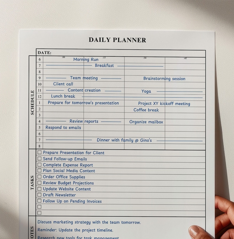 A "daily planner" template on a white sheet of paper held by a hand against a light beige background.