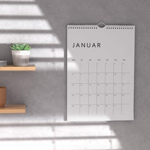 Minimalistischer deutscher Kalender 2026 auf weißem Papier, ein Monatsblatt im Hochformat A4, klare Linien und moderne Typografie, liegt auf hellem neutralem Hintergrund, druckbare PDF-Vorlage.