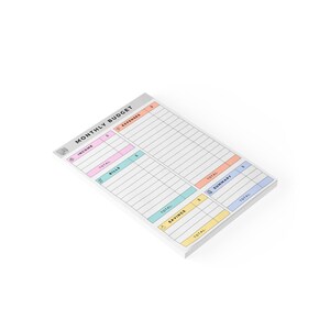 Close-up of a sticky note financial planner featuring pastel tones and cute icons for income, bills, expenses, and savings categories printed on uncoated white paper.