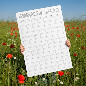 May include: A large white calendar for Summer 2026 is held up in a field of green grass, red poppies, and white daisies. The calendar grid is visible, with the words "SUMMER 2026" at the top. The calendar is held by a person.