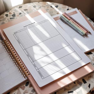 Flat lay of a printable daily planner page, showcasing minimalist sections for scheduling, task management, and notes.