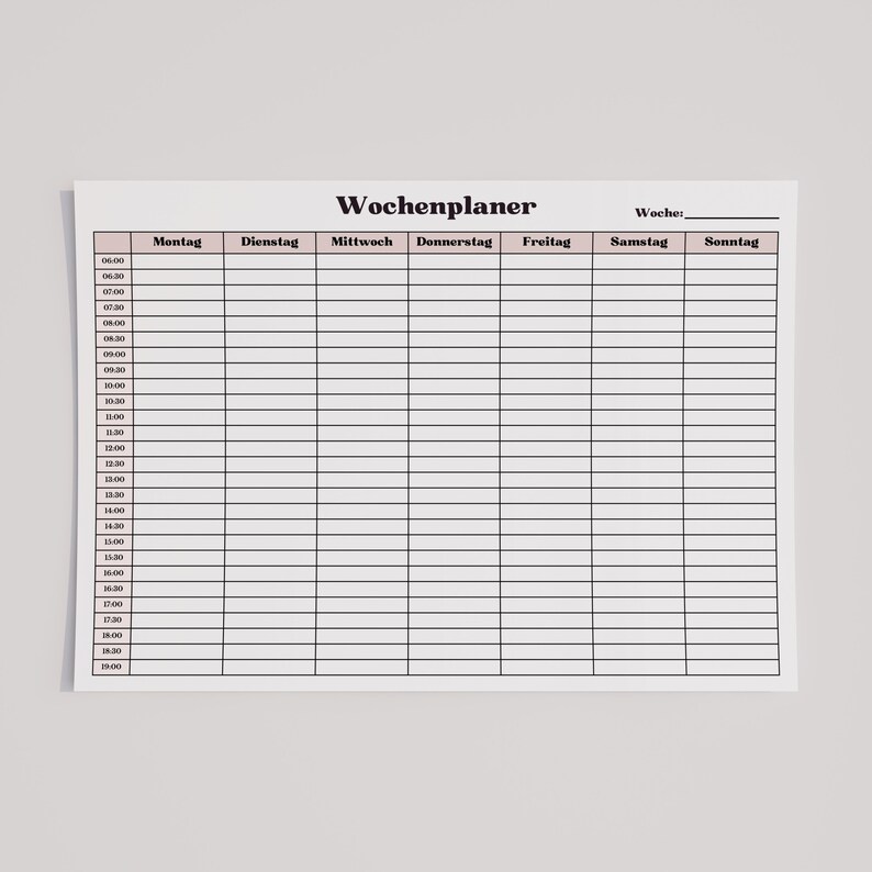 Minimalistische Wochenübersicht auf weißem Blatt Papier mit Zeitplan von Montag bis Sonntag und halbstündigen Zeitblöcken, zarte rosa Spaltenüberschriften, klare Linien, flach auf neutraler Oberfläche fotografiert.