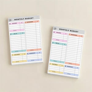 Top-down view of sticky note budget pad with 50 sheets, pastel headers dividing income, expenses, savings, and bills, compact design suitable for planners, desks, or portable use.