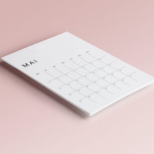 Monatsplaner 2026 Deutsch, minimalistisches PDF-Design auf weißem A4-Blatt gedruckt, feine Linien, moderne Schrift, flach auf hellem Untergrund fotografiert.