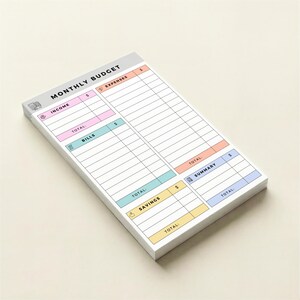 Small 4x6 Post-it style notepad for tracking bills, income, savings, and expenses with pastel headers and icons, single-sided printed sheets neatly stacked for personal budgeting at home or office.
