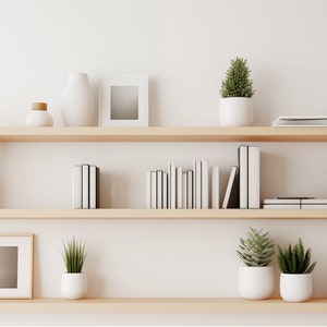 May include: Two wooden shelves with white vases, potted plants, books, and framed pictures. The shelves are against a white wall.