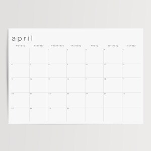 Minimalist July 2026 monthly page displayed on semi-gloss paper against grey tabletop. The landscape planner shows a thin-line grid, weekday labels along the top, and uniform date numbers.