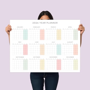May include: A white 2026 year planner with a minimalist design. The calendar features monthly grids with pastel color highlights for each month. The text "2026 YEAR PLANNER" is at the top.