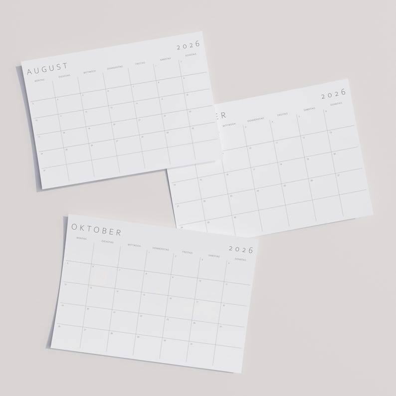 2026 Monatskalender auf A3-Papier im Querformat mit minimalistischen grauen Linien und moderner Typografie, liegend auf neutraler Oberfläche.