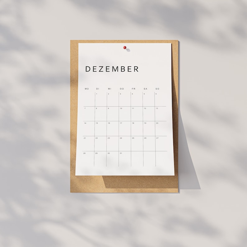 Monatsübersicht aus dem Kalender 2026 Deutsch, gedruckt im minimalistischen Stil auf weißem Papier, klare Linien und moderne Typo, liegt auf neutraler beige-grauer Oberfläche.