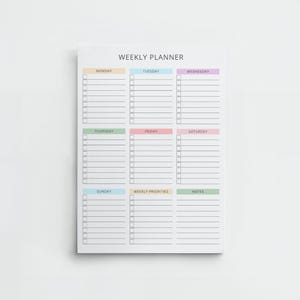 Peut inclure: Un bloc-notes planificateur hebdomadaire blanc avec des sections pour chaque jour de la semaine, y compris "Weekly Priorities" et "Notes". Chaque jour est codé par couleur avec des teintes pastel. Le texte "WEEKLY PLANNER" est en haut.