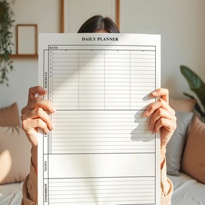 Puede incluir: Un planificador diario blanco con el texto "DAILY PLANNER" en la parte superior. El planificador incluye secciones para la fecha, el horario, las tareas, las notas y el ma&ntilde;ana. El planificador est&aacute; sostenido por una persona.