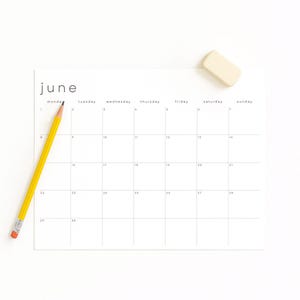 April 2026 monthly calendar sheet printed on matte paper, positioned on a cream desktop. Clean landscape design with pale lines, thin modern text, and Sunday start column visible on the left side.