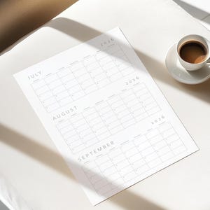 One quarter of the 2026 calendar printed in portrait orientation with three months per page, thin line design and grey font, photographed flat on a white paper sheet over a plain background.